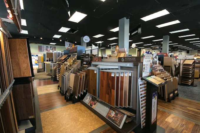 Interior of City Carpets showroom displaying a wide variety of hardwood, laminate, and vinyl flooring samples arranged in organized racks under bright ceiling lights.