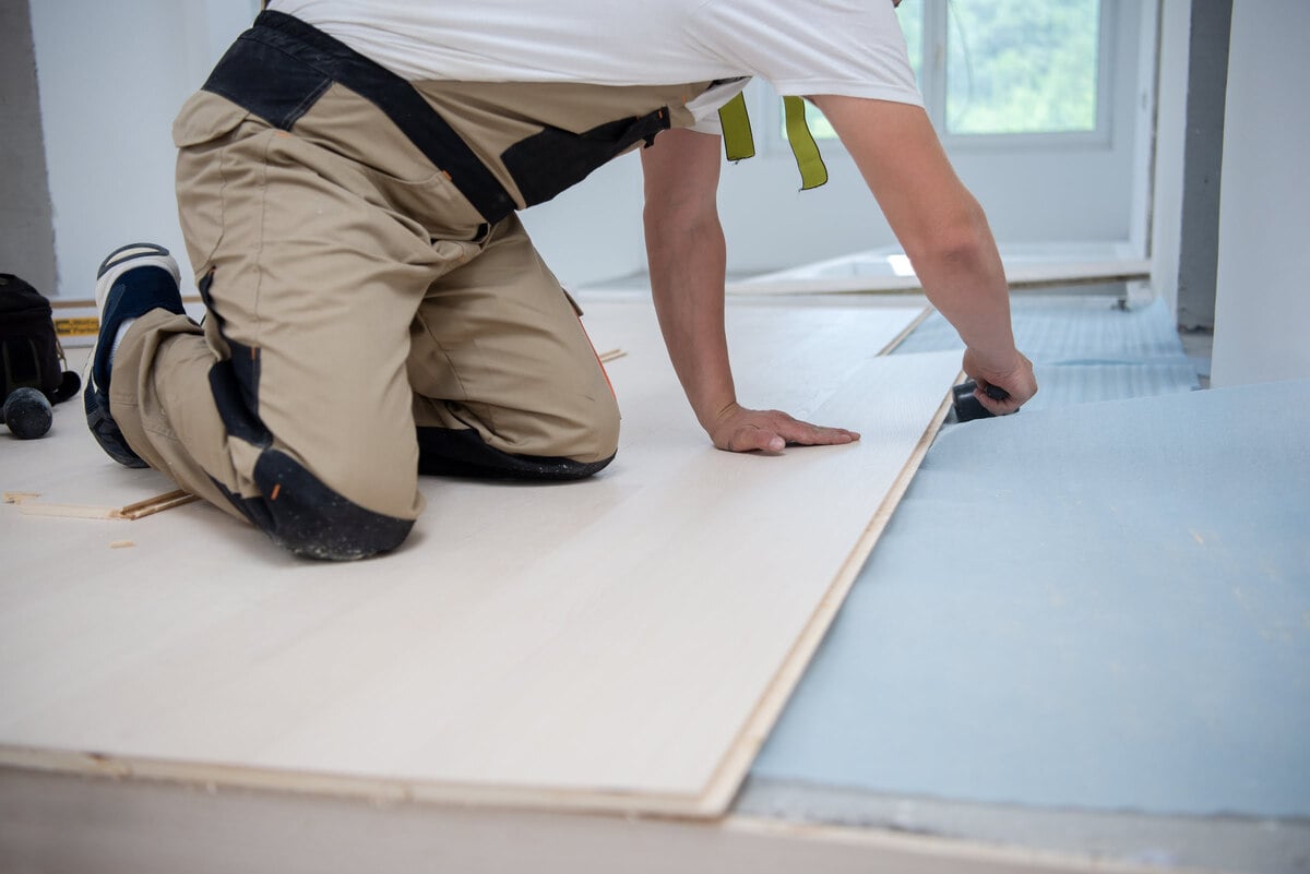 A man is installing wood flooring.