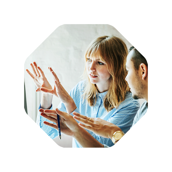 A woman and a man in discussion, gesturing towards an idea or concept, possibly related to design planning.