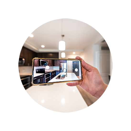 A person holding a smartphone in a modern kitchen, using an AR-based tool to visualize a new kitchen design on the screen.