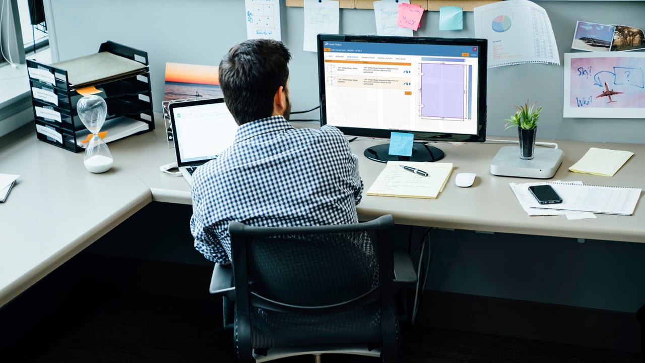 A man seated at a desk, focused on his computer.