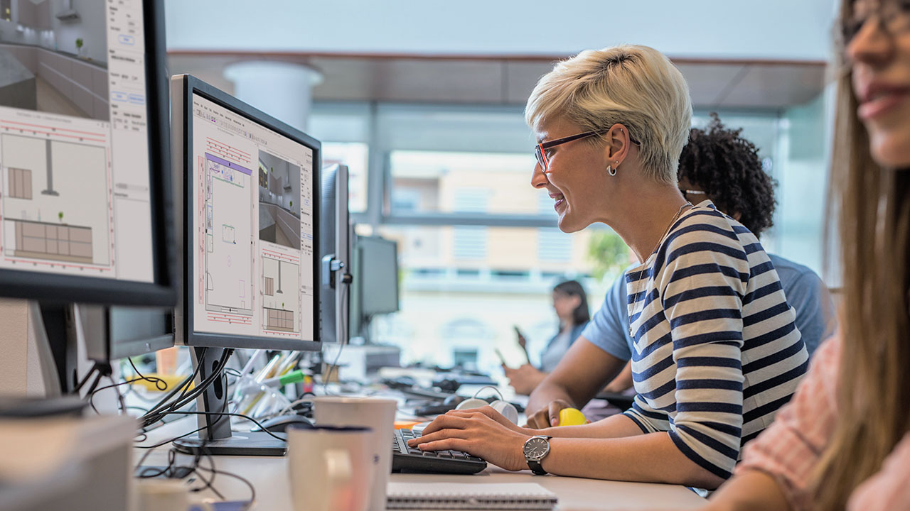 A professional woman engaged in computer work at her office desk.