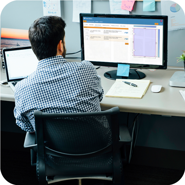 A man working diligently at a desk, with a computer and a laptop.