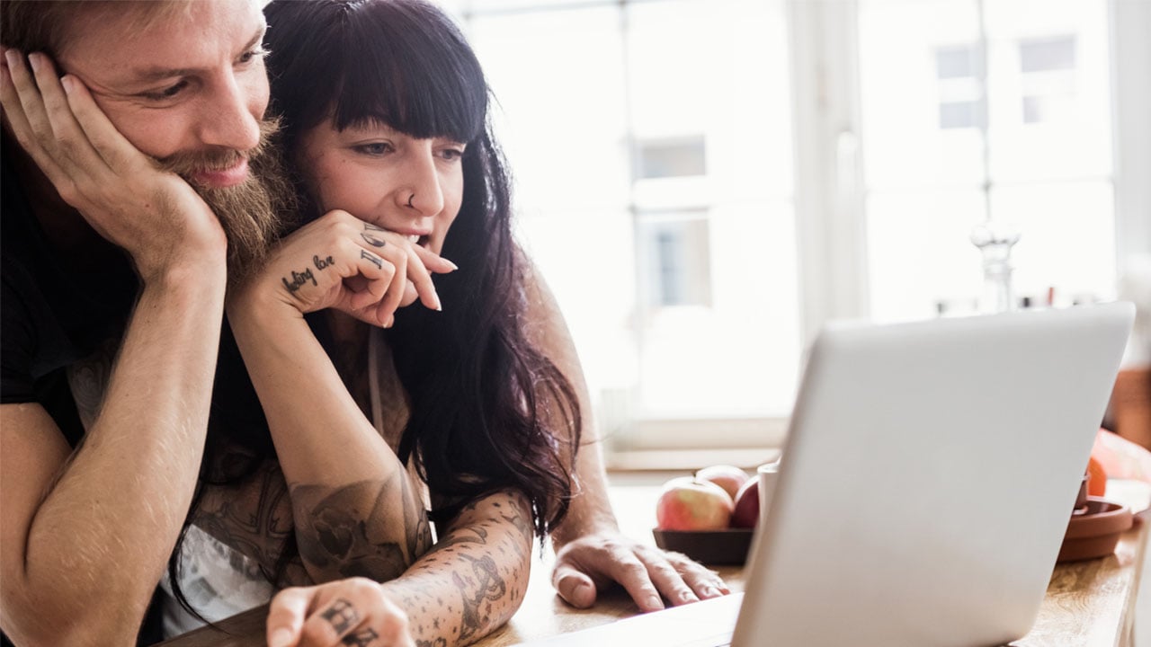 A man and woman focused on a laptop screen.