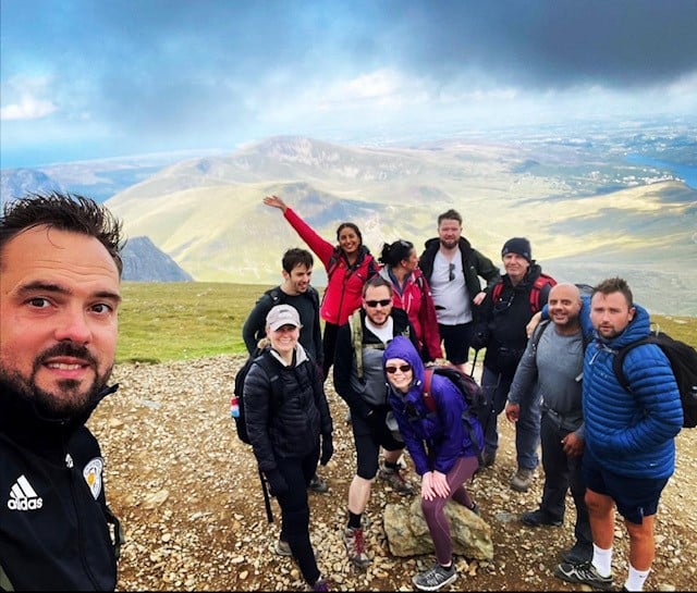 A group of hikers celebrating on a mountain summit.