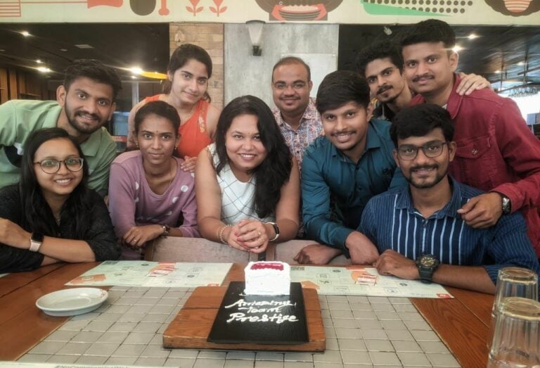 A group of people smiling and posing for a photo with a cake.