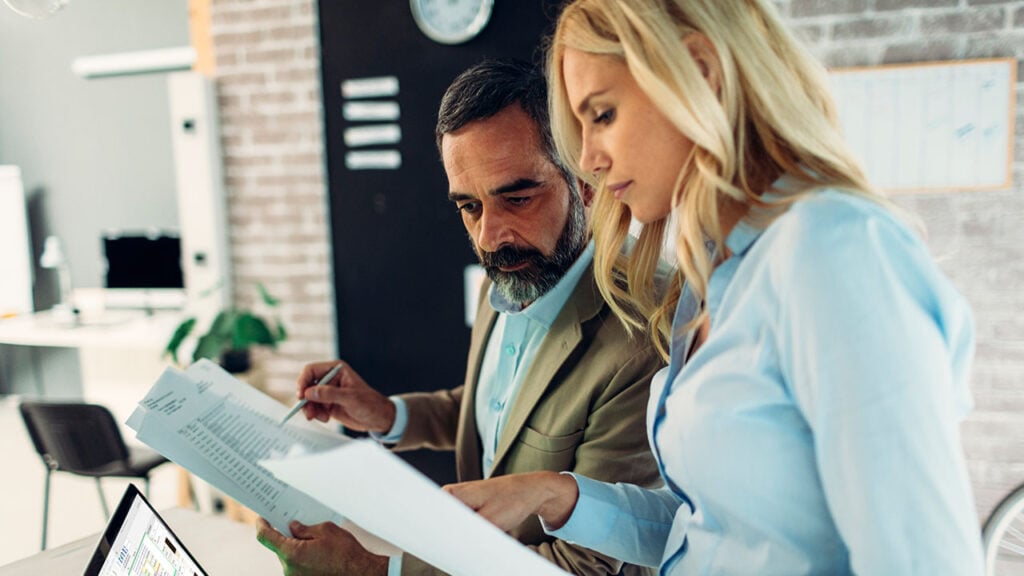 A man and woman reviewing documents in an office setting.