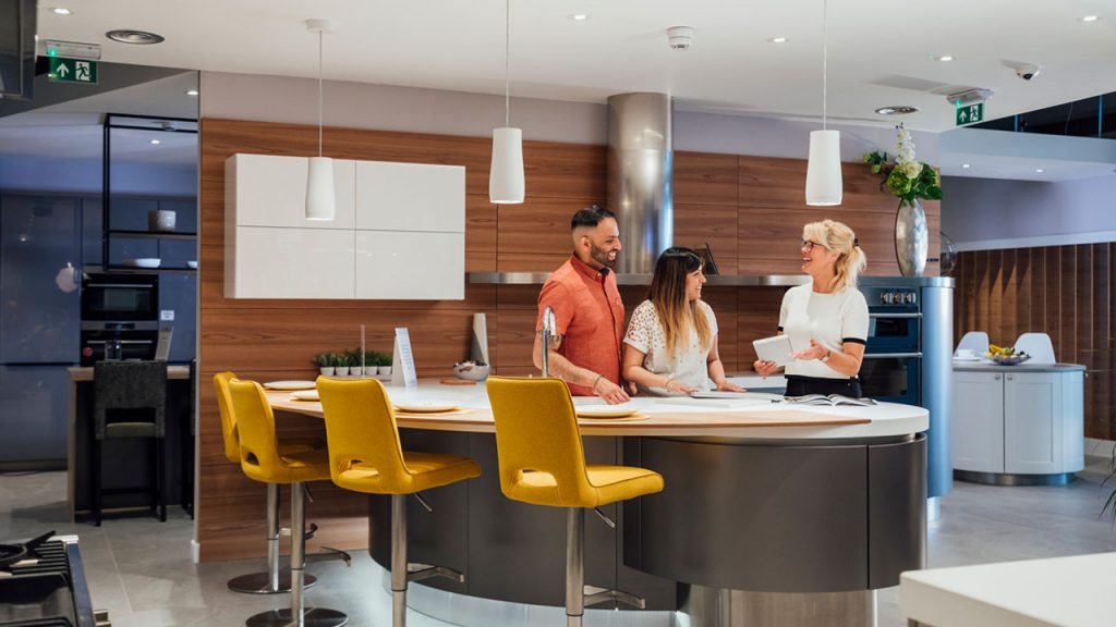 A couple standing in a modern kitchen with a designer.