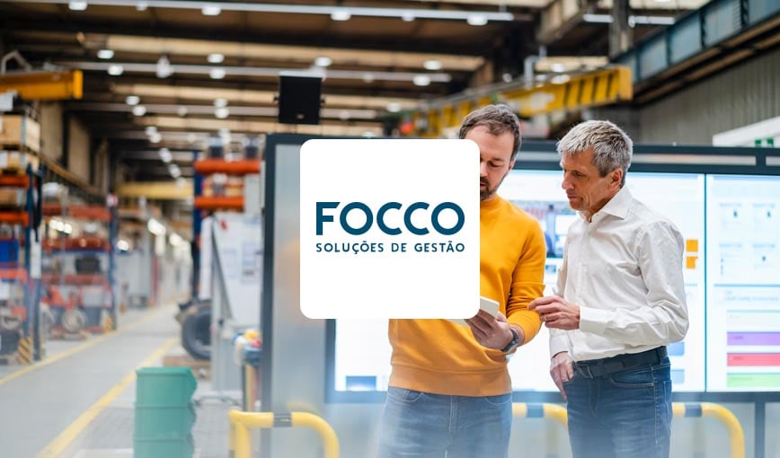 Two men standing in front of a factory with the Focco logo.