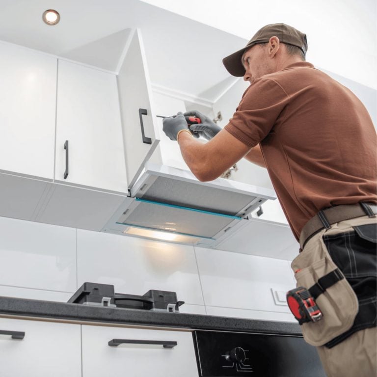 A man repairing a kitchen cabinet with a screwdriver