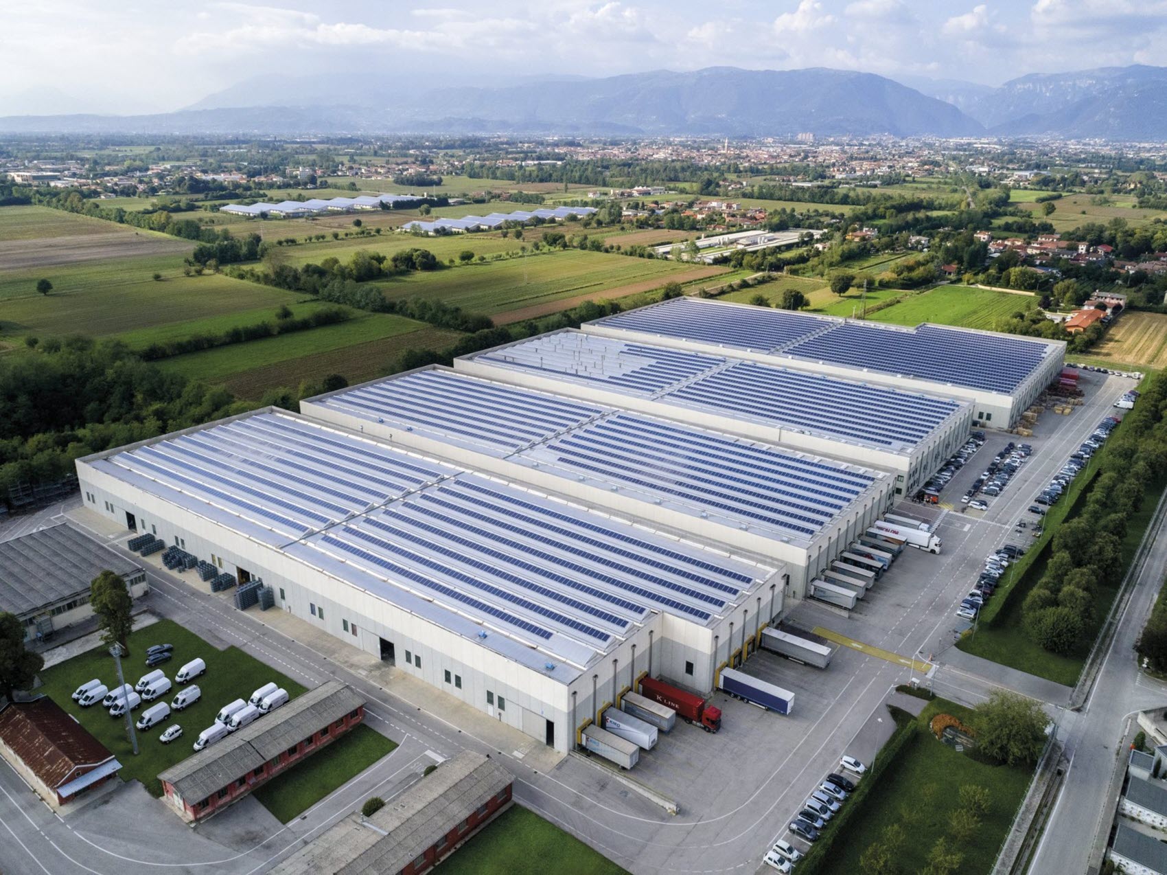 An aerial view of a large industrial facility with multiple warehouses and solar panels on the roof.