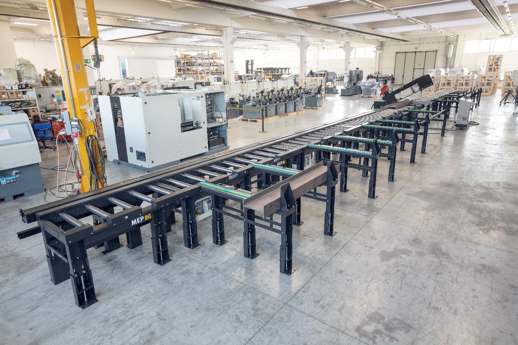 An expansive factory floor with a long conveyor system and various industrial machines.