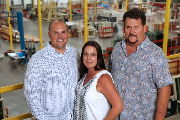 Three Avanti employees standing on a yellow-railed balcony inside a factory