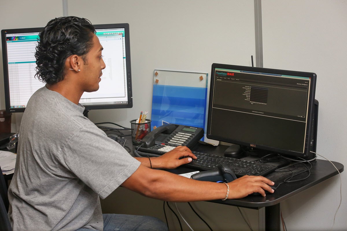 A GlasPro team member working at a computer, utilizing FeneVision MAX software for streamlined glass manufacturing processes.