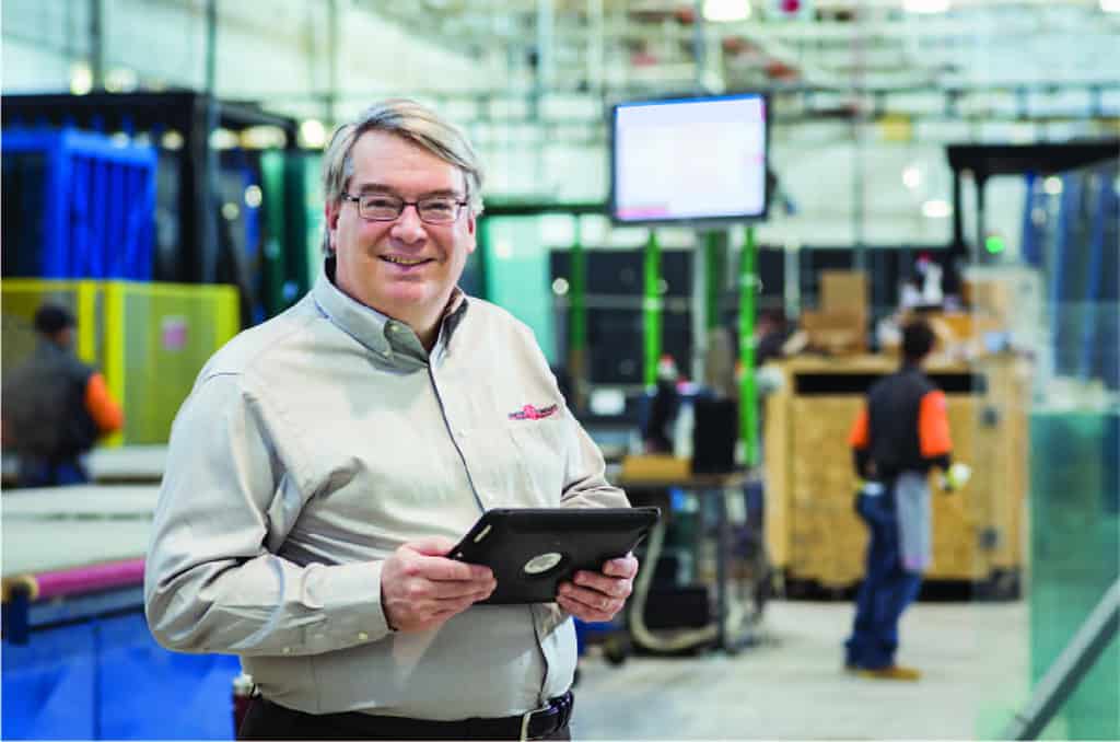 A man is utilizing a tablet in a factory environment