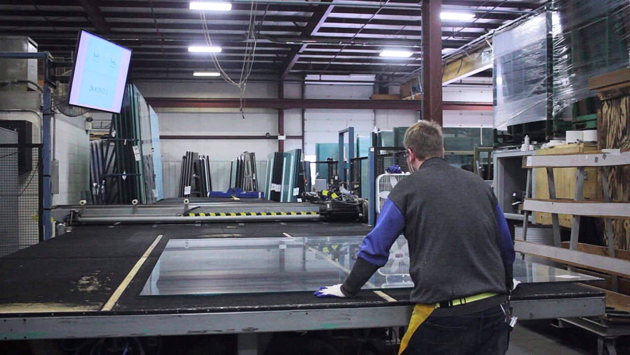 A man working at a glass table in a factory setting