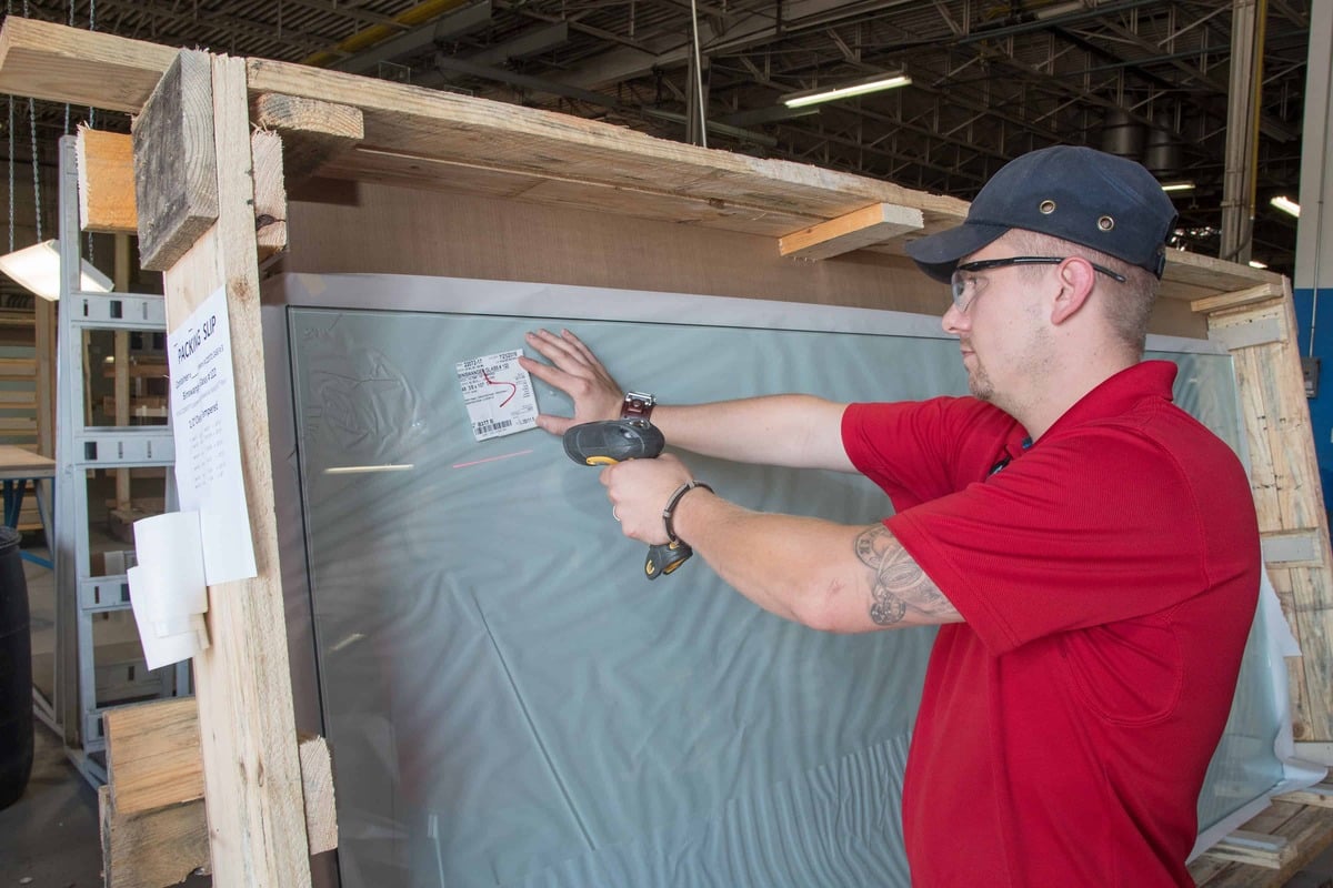 A man operates a power tool to cut through a sheet of glass