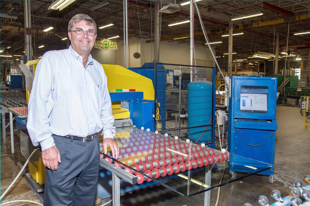 A man stands in front of a factory machine