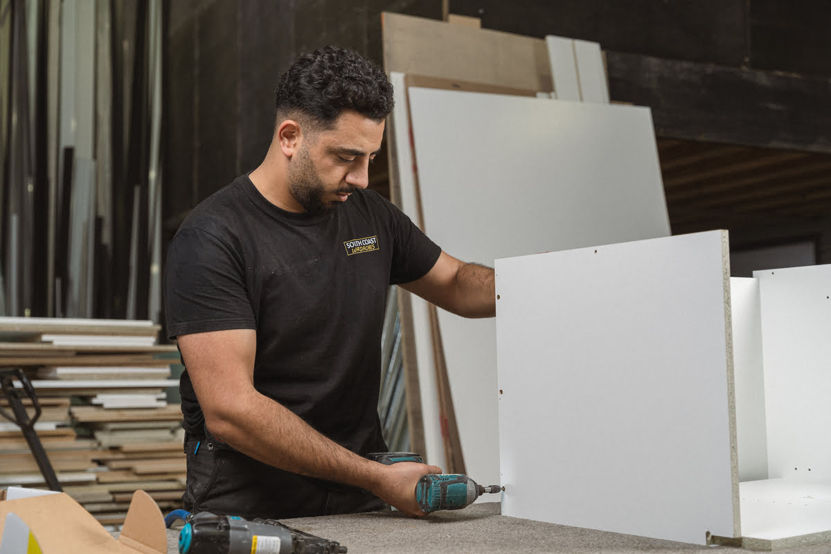 A man works on assembling a cabinet